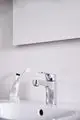 Waschtischarmatur in Chrom von Ideal Standard, ausgestattet mit einem Push-Open-Ventil. Neben einer Zahnbürste und einer Tube Zahnpasta auf einem Waschbecken.